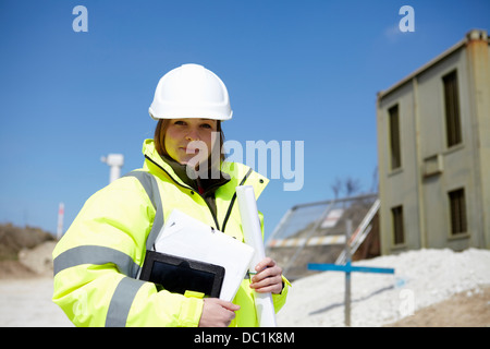 Portrait of female with blueprint and digital tablet on construction site Stock Photo