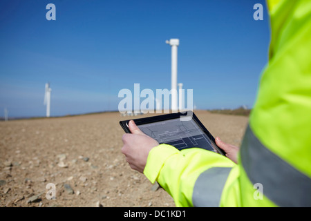 Project manager using digital tablet in front of wind farm Stock Photo