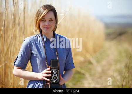 Close up portrait of young woman holding camera Stock Photo