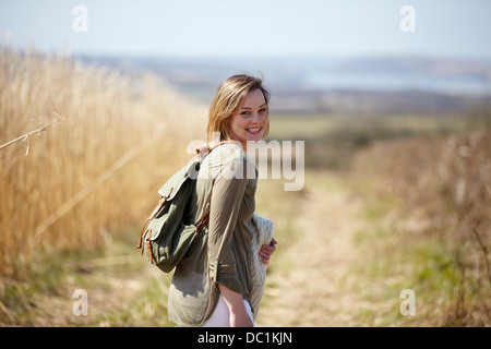 Portrait of young woman on dirt track next to field of reeds