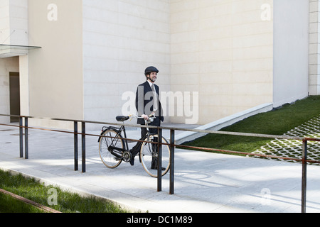 Mid adult businessman walking with bicycle Stock Photo