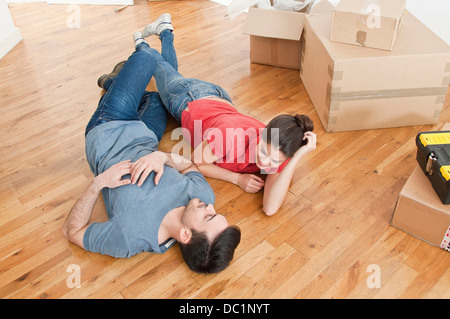 Young couple lying on floor amongst cardboard boxes Stock Photo