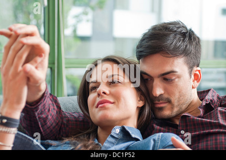Young couple lounging on sofa holding hands