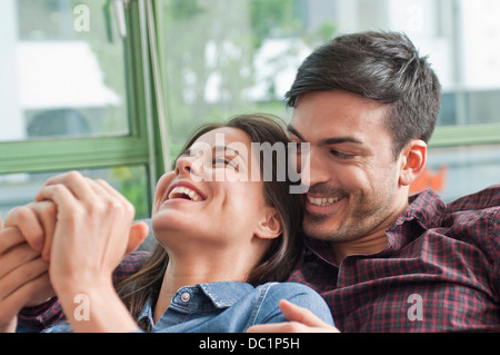 Romantic young couple laughing on sofa Stock Photo