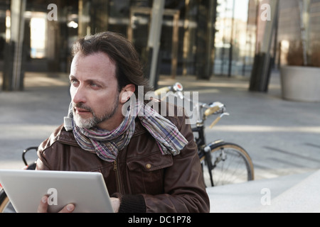 Mid adult man using digital tablet in city