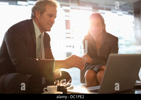 Businessman and businesswoman using laptop in lobby Stock Photo
