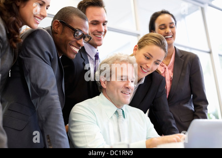 Smiling business people sharing laptop in meeting Stock Photo