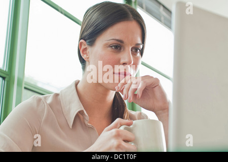 Young female office worker looking at laptop Stock Photo