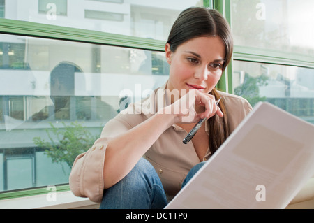Young female reading documentation in office Stock Photo