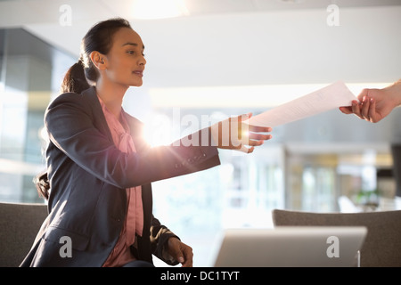 Businesswoman reaching for paperwork Stock Photo