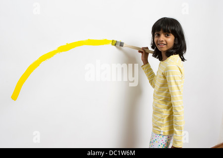 Portrait of girl painting yellow curve on wall Stock Photo