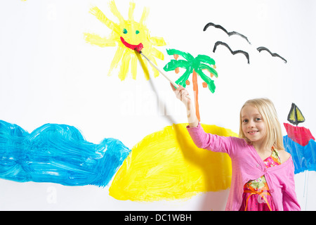 Young girl painting smiling sunshine face on wall Stock Photo