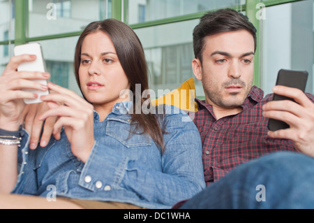 Young couple at home using mobile phones Stock Photo