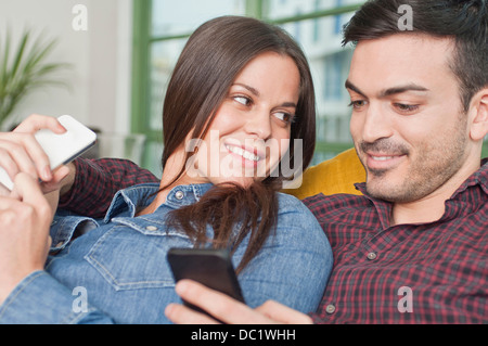Young couple at home using mobile phones Stock Photo