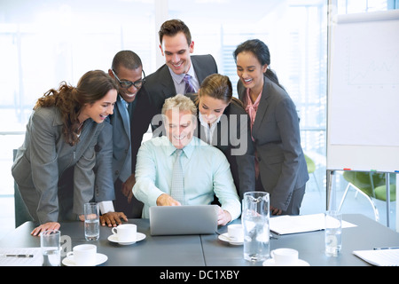 Smiling business people sharing laptop in conference room Stock Photo