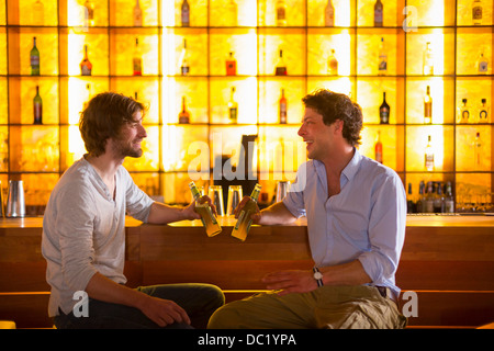 Two men sitting at bar with bottles of beer Stock Photo