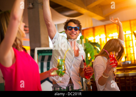 Group of friends dancing with cocktails in bar Stock Photo