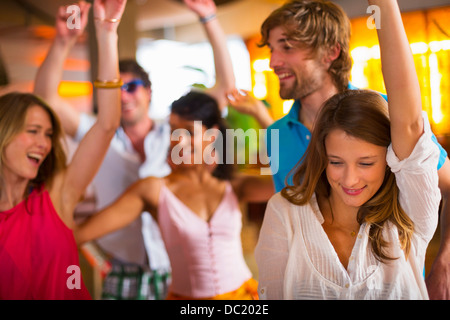 Friends dancing with arms up in bar Stock Photo