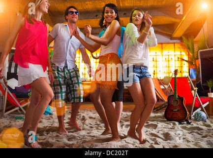 Friends dancing on sand at indoor beach bar Stock Photo