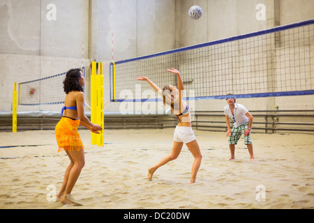 Friends playing indoor beach volleyball Stock Photo