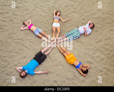 Aerial view of friends lying in star shape on sand Stock Photo