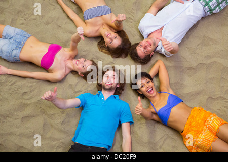 Aerial view of friends lying with heads together on sand Stock Photo