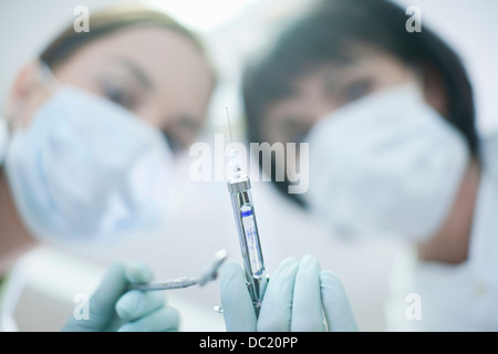 Portrait of dentist and dental nurse holding syringe Stock Photo