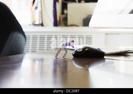 Businesswoman pushing large computer mouse on oversized desk Stock Photo