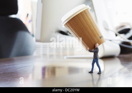 Mature businessman carrying large disposable cup on oversized desk Stock Photo