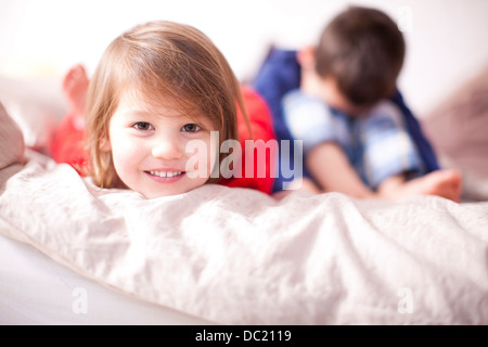 Portrait of young girl smiling and brother sulking Stock Photo