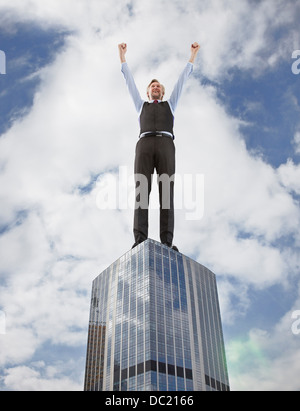 Oversized businessman cheering on skyscraper, low angle view Stock Photo