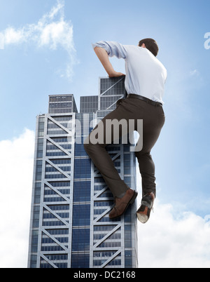 Oversized businessman climbing skyscraper, low angle view Stock Photo