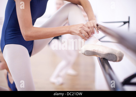 Ballerina fastening ballet slipper at the barre Stock Photo