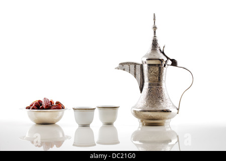 A dallah, a metal pot for making Arabic coffee with a bowl of dried dates Stock Photo