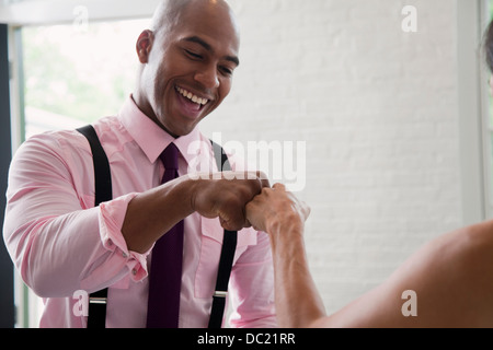 Mid adult man fist bumping colleague and smiling