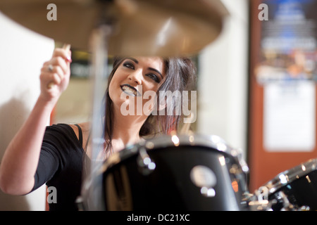 Young woman playing drum kit in music store Stock Photo