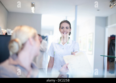 Nurse handing file to hospital receptionist Stock Photo