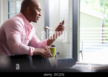 Mid adult man sitting on sofa looking at mobile phone