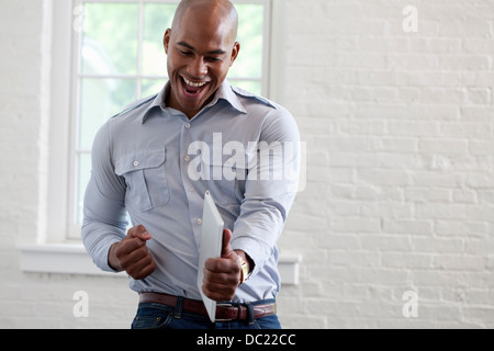 Mid adult office worker holding digital tablet and punching air