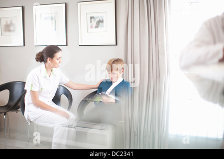 Nurse chatting to young patient in hospital reception Stock Photo