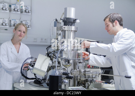 Two scientists wearing lab coats using scientific equipment Stock Photo