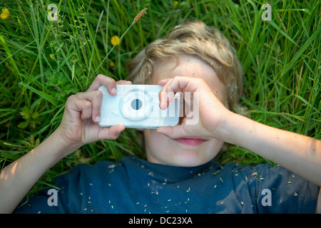 Boy lying on grass taking photograph using smartphone Stock Photo