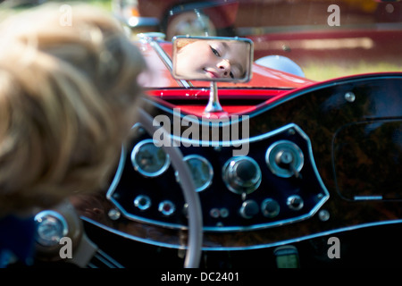 Boy sitting in driver's seat looking in rear view mirror Stock Photo