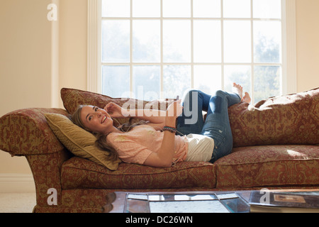 Teenage girl lying on sofa with earphones Stock Photo