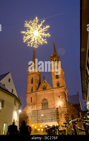 Switzerland, Basel. Historic church at Munsterplatz Winter Holiday Market. Christmas lights on a snowy winter night at plaza. Stock Photo