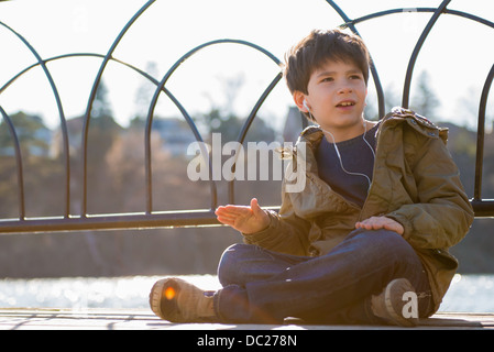 Boy sitting cross legged wearing earphones Stock Photo