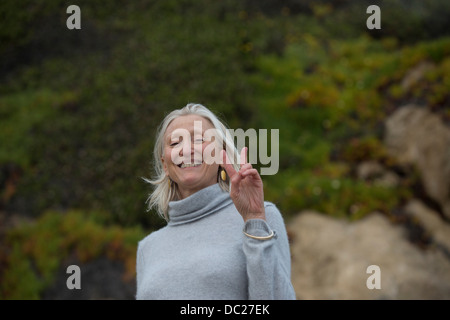 Mature woman making victory sign Stock Photo