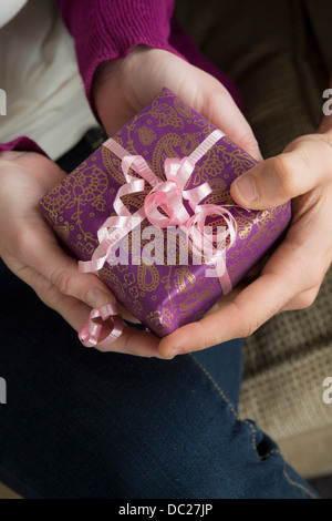 Two people holding gift box with pink ribbon Stock Photo