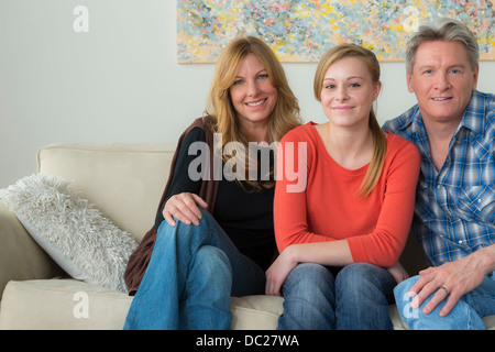 Portrait of mother and father with teenage daughter on sofa Stock Photo