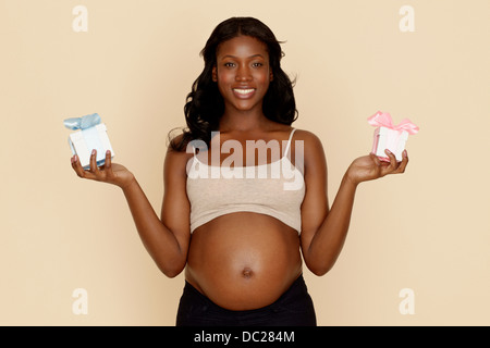 Pregnant young woman holding blue and pink gift boxes Stock Photo